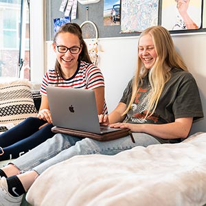Aquinas students in college room using a laptop