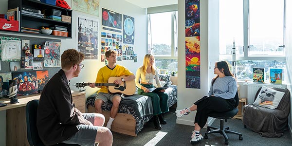 Hayward students playing guitar in college room