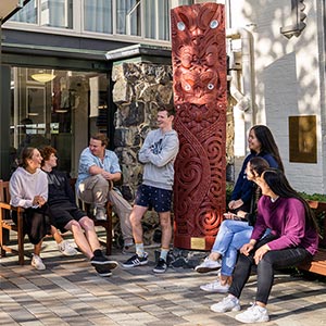 Studholme students talking beside carving outside of entrance